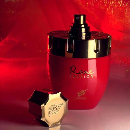 Afnan Rare Passion Eau De Parfum bottle in red and gold design with its cap placed beside it on a reflective surface under warm red lighting