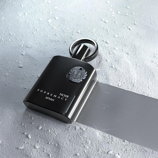Afnan Supremacy Noir Eau De Parfum bottle on textured surface.