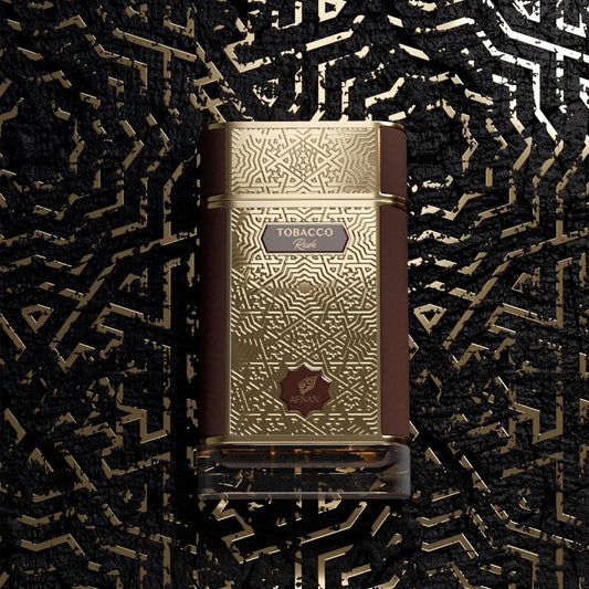 Afnan Tobacco Rush Eau De Parfum bottle in luxurious gold and brown design with intricate geometric patterns displayed on a matching textured gold-black background