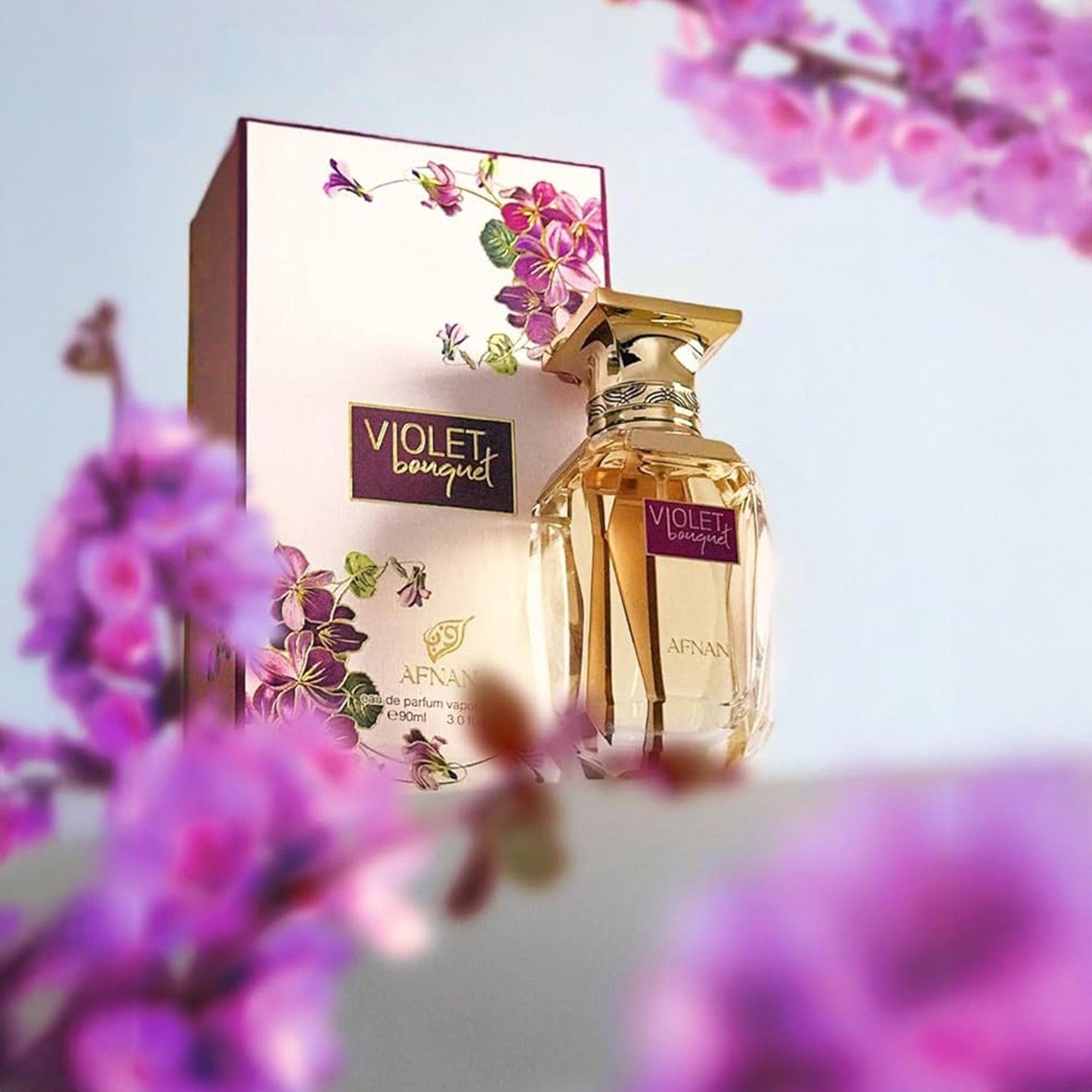 Afnan Violet Bouquet Eau De Parfum bottle and box design surrounded by blooming purple flowers with a soft pastel background