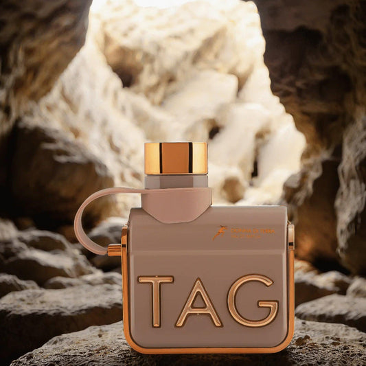 Armaf Tag Her Donna Di Terra EDP beige and gold bottle placed on rocky terrain with a cave-like background and natural light