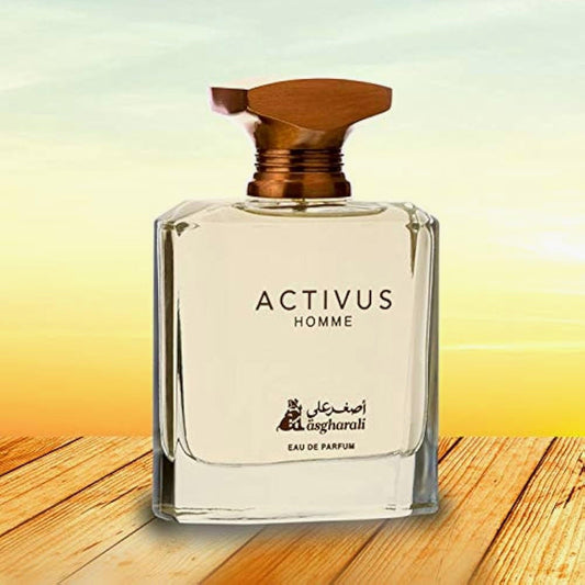 Asgharali Activus Homme Eau De Parfum clear glass bottle with wooden cap placed on wooden surface against a golden sunrise background