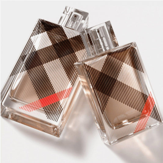 Burberry Brit perfume bottles with the signature plaid design and a touch of red accent placed on a light background, showcasing modern elegance