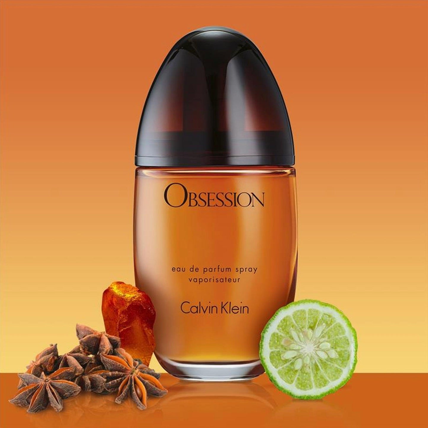 Calvin Klein Obsession Eau De Parfum amber-toned bottle with lime, star anise, and resin accents on a warm orange background