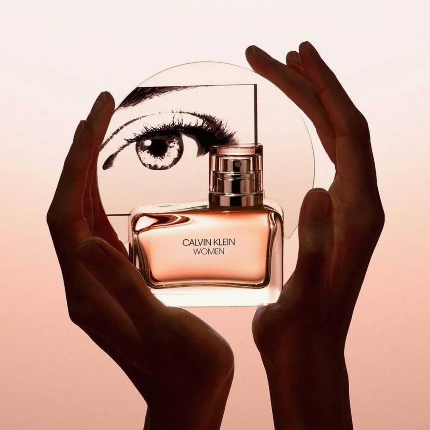 Calvin Klein Women Eau De Parfum bottle held between hands with artistic eye illustration in the background on a beige gradient backdrop