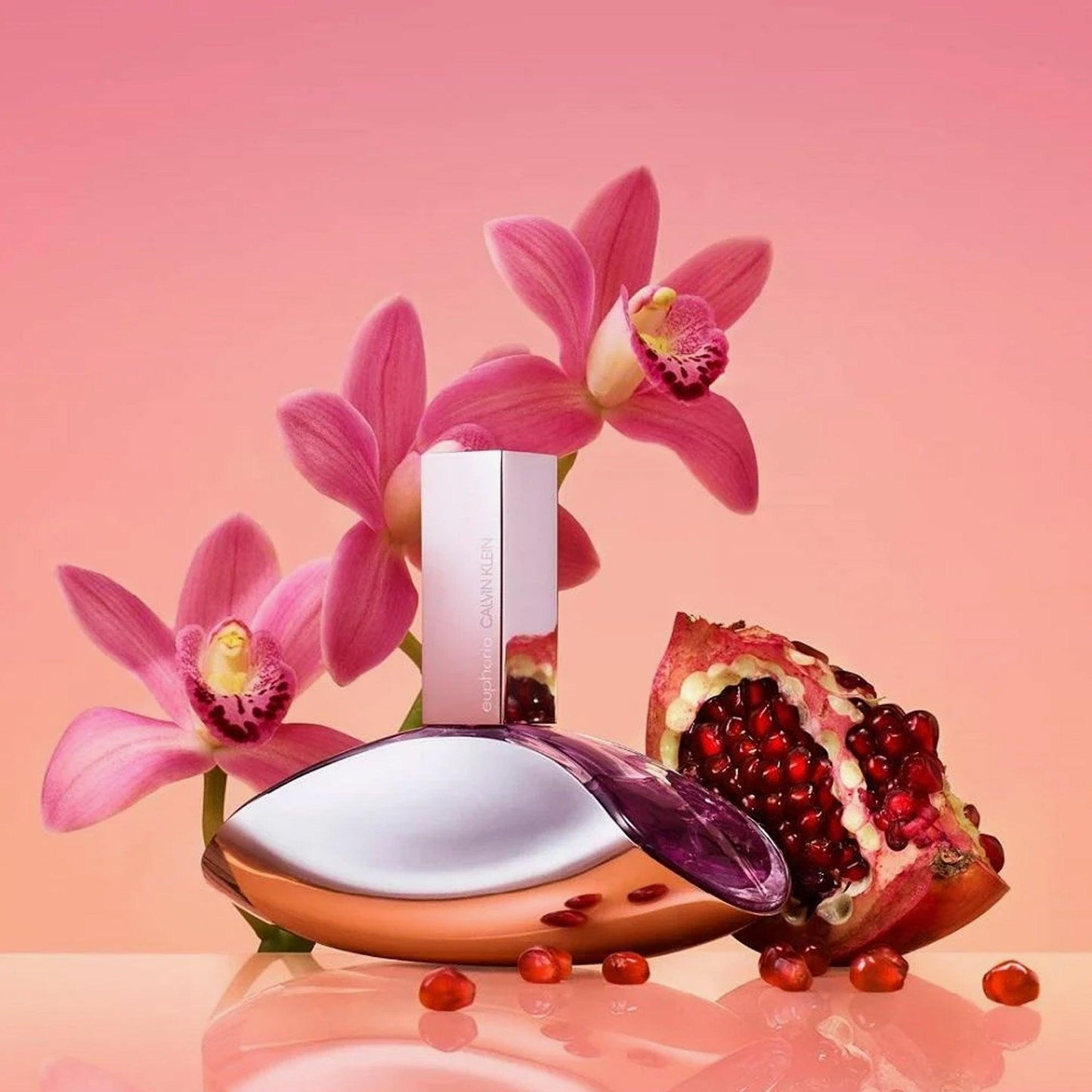 Calvin Klein Euphoria Perfume bottle with pink orchids and pomegranate on a soft pink gradient background