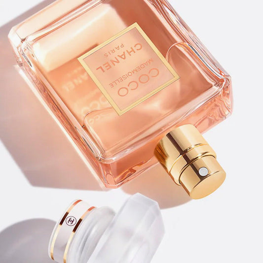 Chanel Coco Mademoiselle perfume bottle with gold nozzle on a soft pastel background