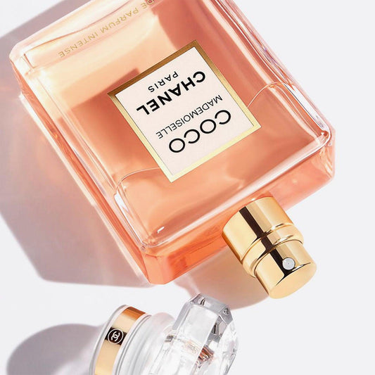 Chanel Coco Mademoiselle Intense perfume bottle with gold nozzle on pastel background.