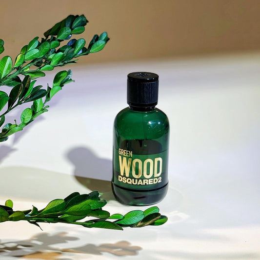 DSQUARED2 Green Wood perfume bottle in dark green glass with leaves on white surface