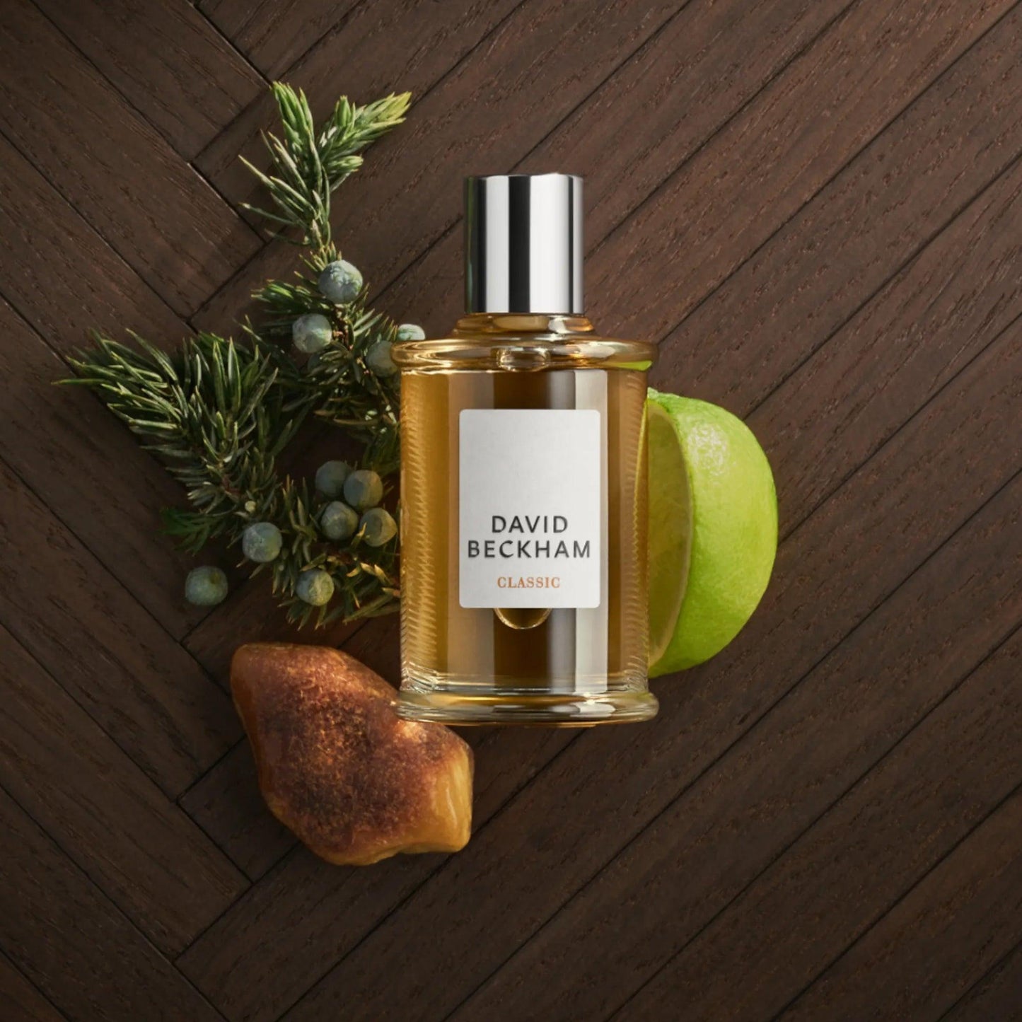 David Beckham Classic perfume bottle with green apple, amber, and juniper berries on a wooden textured surface, symbolizing a fresh, woody masculine fragrance style