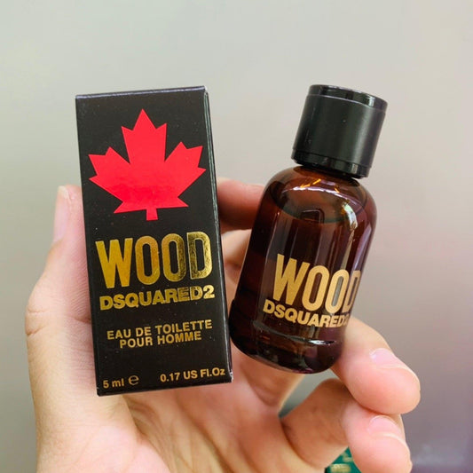 DSQUARED2 Wood Pour Homme mini brown bottle held beside black box with red maple leaf.