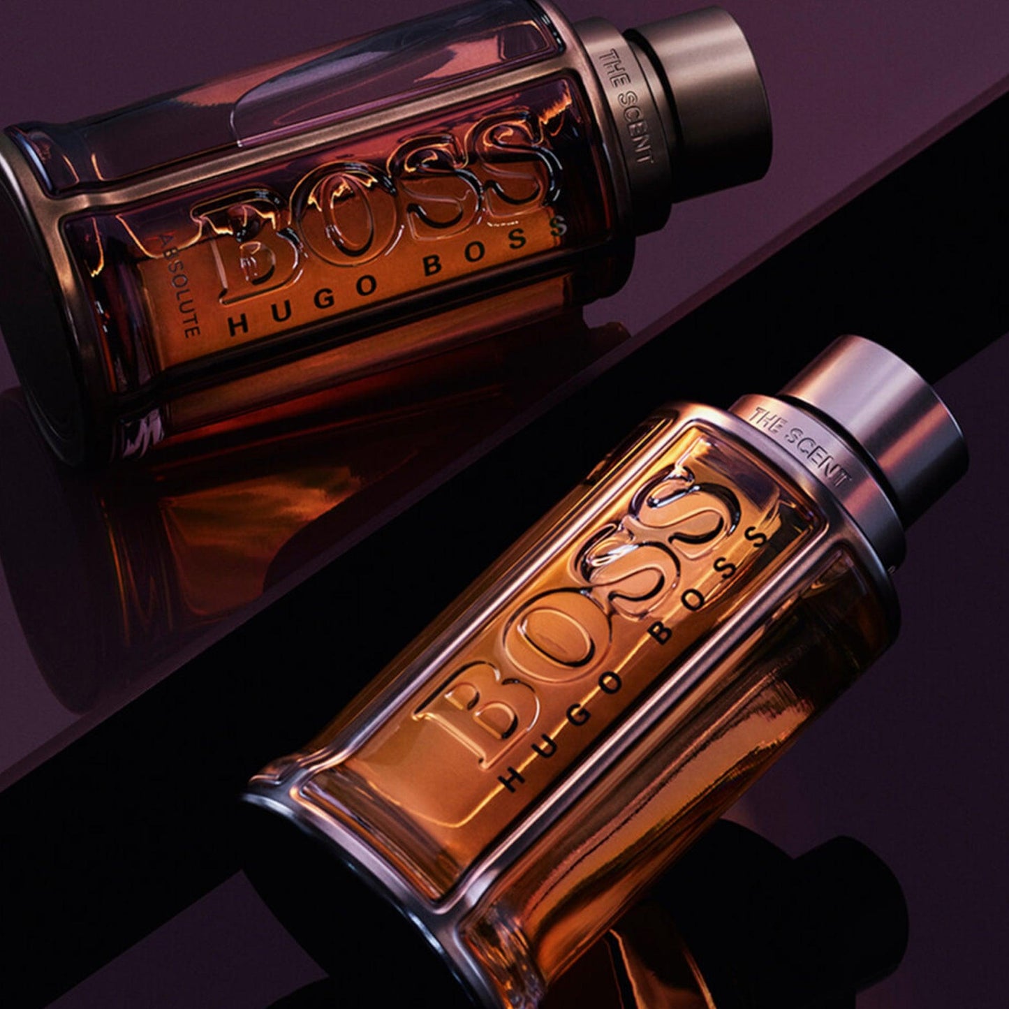 Hugo Boss The Scent Absolute Eau De Parfum bottles for men displayed on a glossy dark surface, highlighting their amber tones and elegant design.
