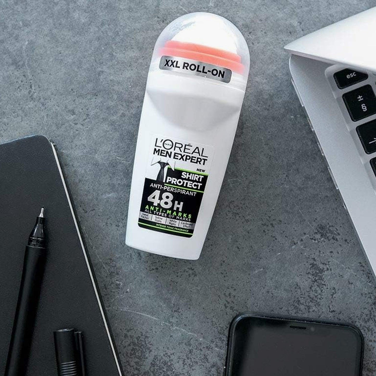 L’Oreal Men Expert Shirt Protect 48H XXL roll-on deodorant placed on a gray desk beside a laptop, phone, and notebook, highlighting its sleek white design and anti-mark formula
