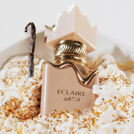lattafa Eclaire perfume bottle with gold details on whipped cream and vanilla pod with golden flakes
