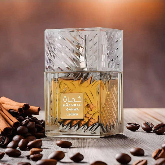 Lattafa Khamrah Qahwa perfume bottle with golden liquid surrounded by coffee beans and cinnamon.