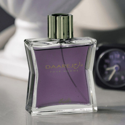 Rasasi Daarej Pour Homme Eau De Parfum bottle with purple liquid and metallic cap placed on a reflective surface beside a blurred background with a clock.