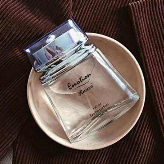Rasasi Emotion Eau De Parfum 100ml bottle placed in a beige ceramic bowl on a dark brown textured fabric background.
