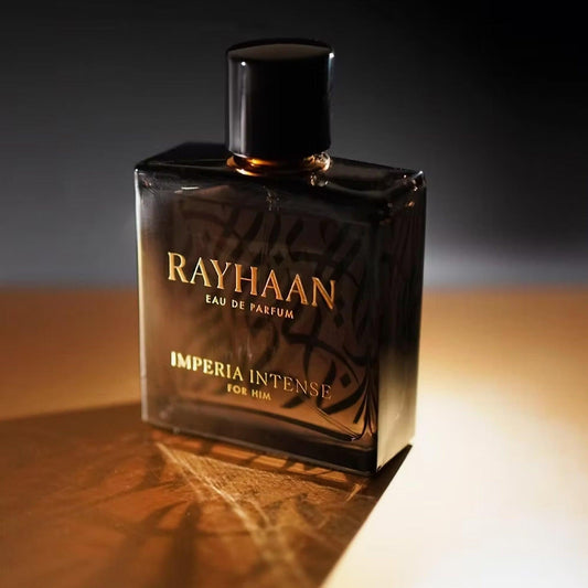 Rayhaan Imperia Intense For Him Eau De Parfum bottle with black and amber tones placed under warm golden lighting on a reflective surface