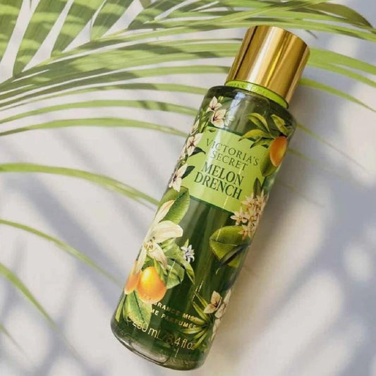 Victorias Secret Melon Drench fragrance mist 250ml bottle with tropical floral design placed under palm leaf shadows on a bright white background