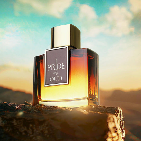 Pride My Oud Eau De Parfum bottle with golden amber gradient design placed on a rock during sunset with mountains and sky in the background