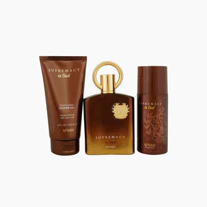 Afnan Supremacy in Oud gift set featuring a brown and gold perfume bottle, matching shower gel, and deodorant, arranged side by side on a white background.
