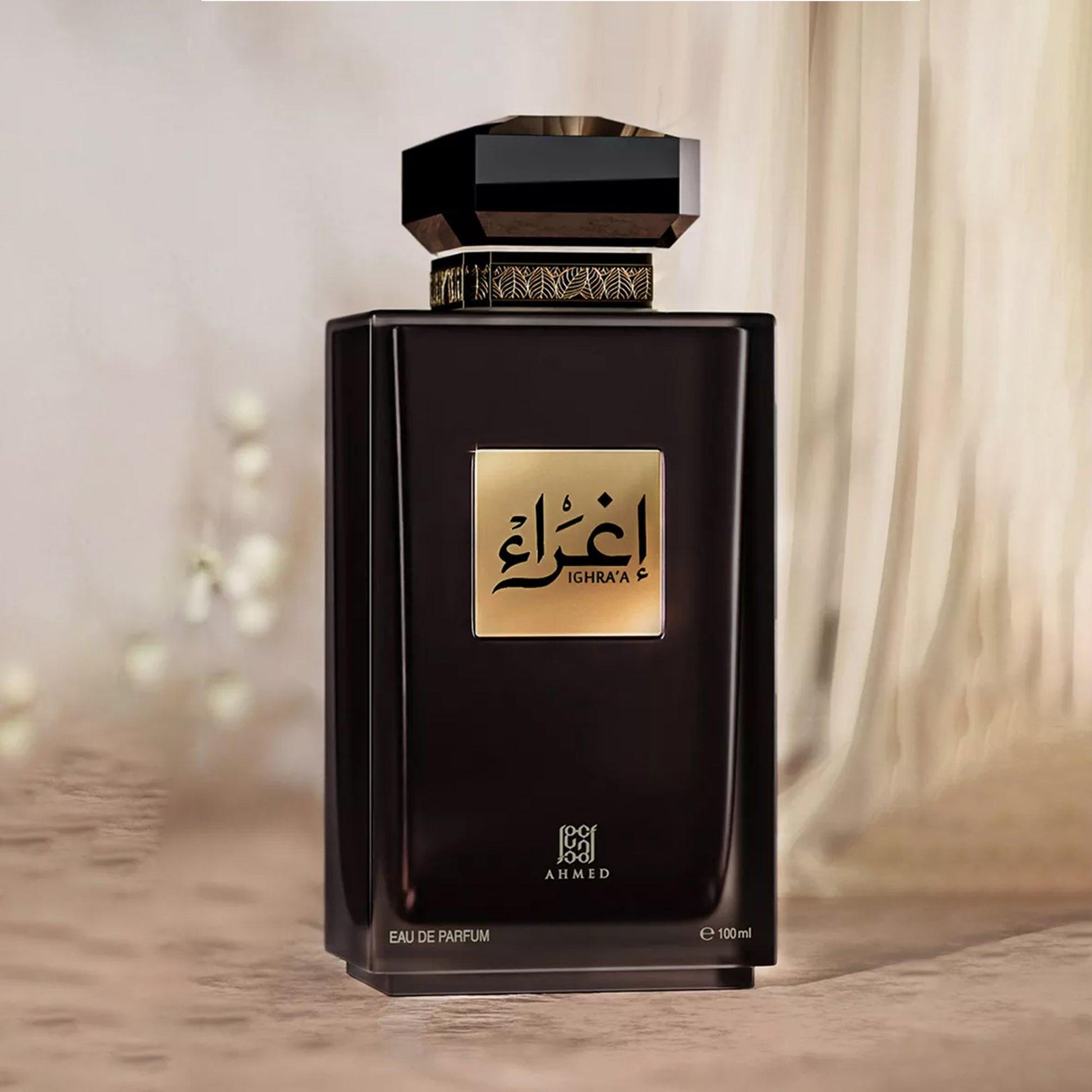 Ahmed Ighraa Eau De Parfum in an elegant black bottle with a gold label and decorative cap, placed against a soft beige curtain backdrop for a luxurious and refined presentation