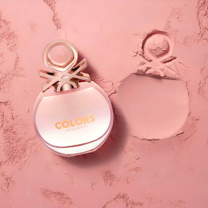 United Colors of Benetton Colors Woman Eau De Toilette bottle placed on a soft pink textured surface with its elegant imprint beside it, highlighting its feminine and playful design