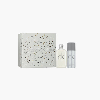 Calvin Klein CK One gift set featuring Eau De Toilette bottle and body spray placed beside a silver and white decorative box on a white background.