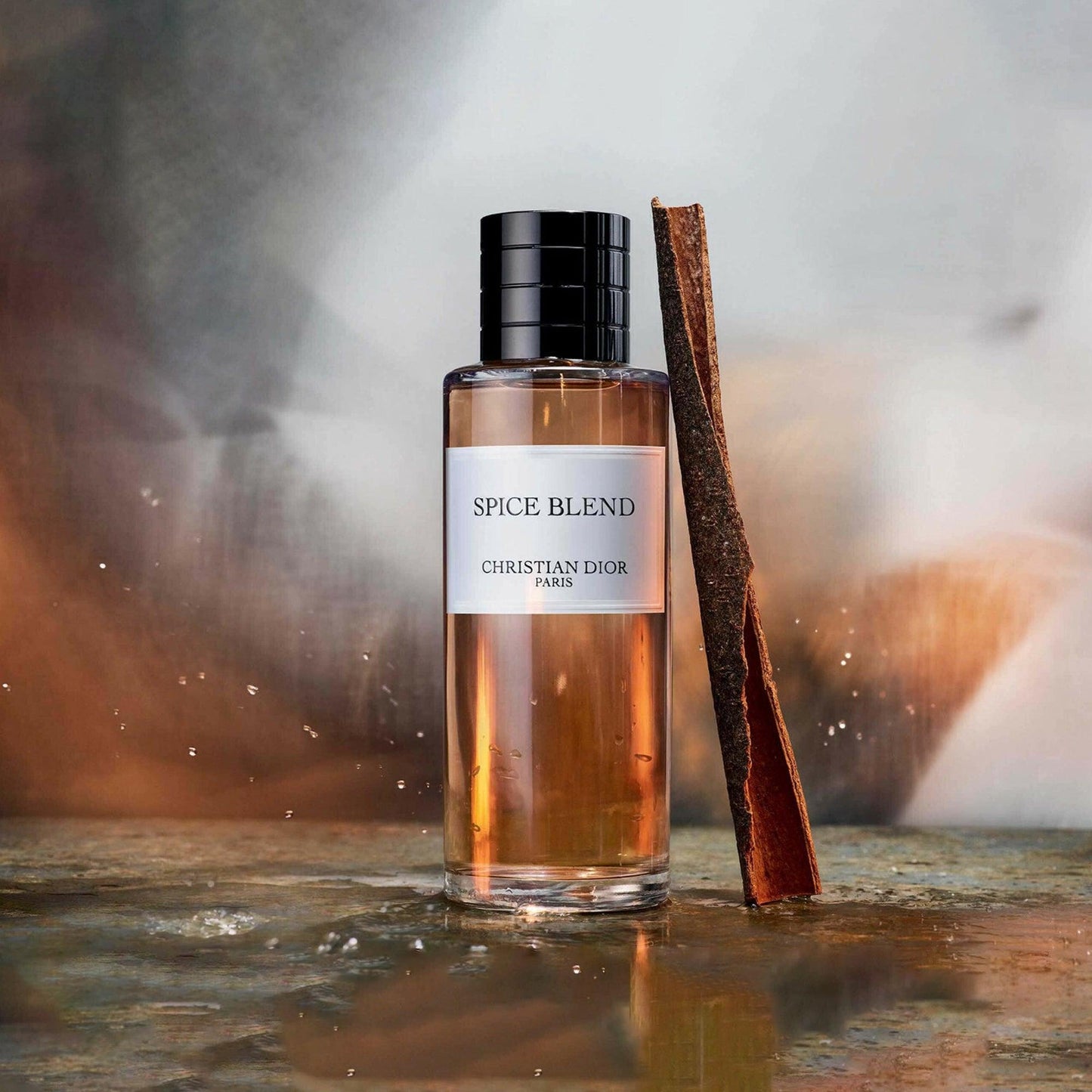 Christian Dior Spice Blend Eau De Parfum bottle with amber liquid placed beside a cinnamon stick on a reflective surface with a warm blurred background