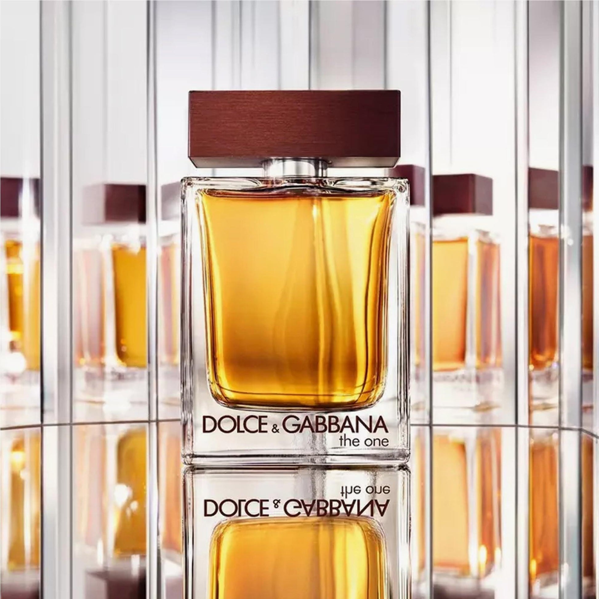 Dolce & Gabbana The One perfume bottle with amber liquid and brown cap displayed against mirrored reflections in a bright setting