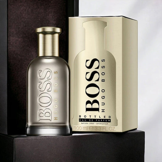 Hugo Boss Bottled Eau De Parfum 100ml for men featuring a sleek metallic bottle placed beside its gold packaging box on a dark background.