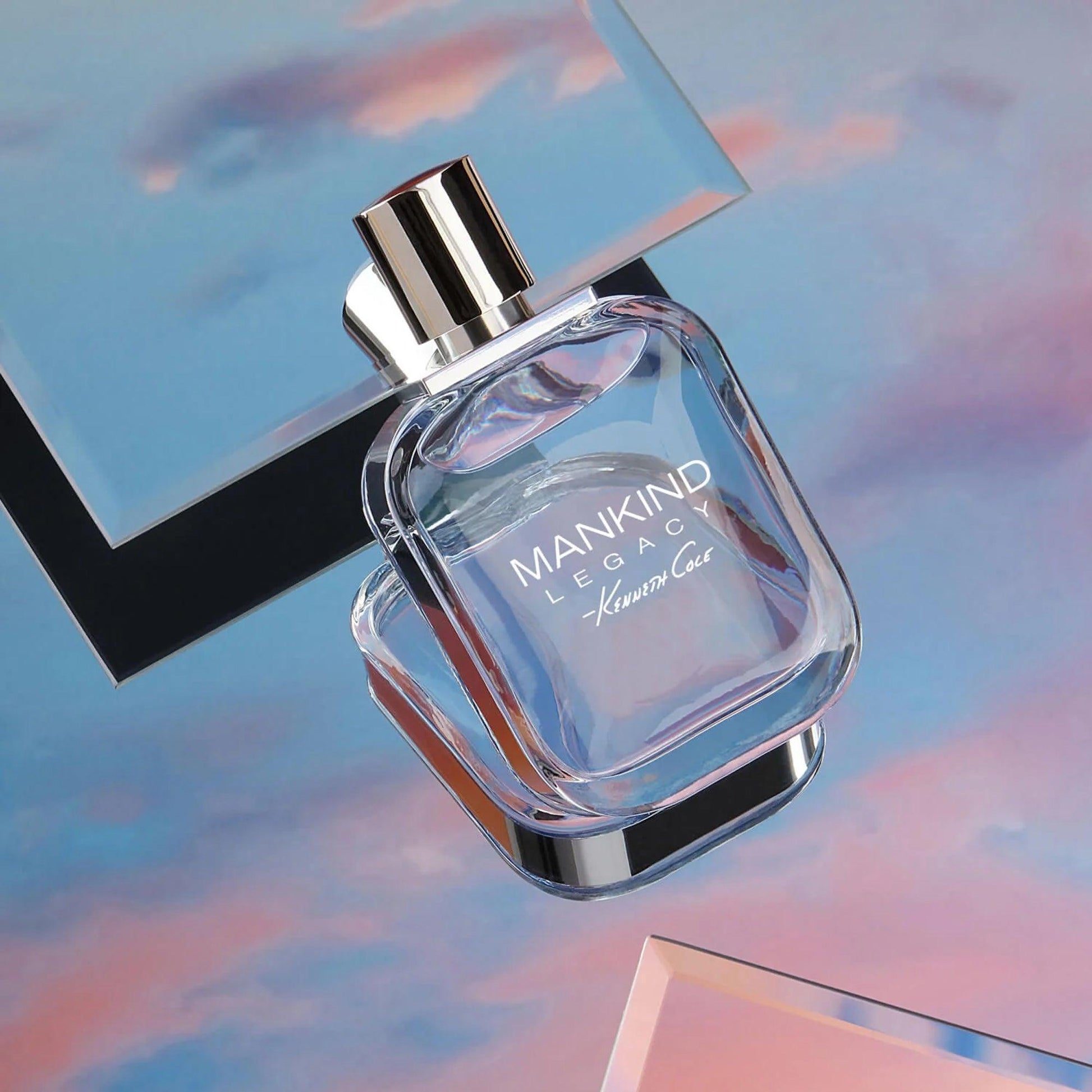 Kenneth Cole Mankind Legacy perfume bottle with a sleek silver cap placed against a dreamy sky-inspired pastel background with pink and blue hues