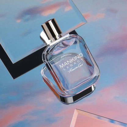 Kenneth Cole Mankind Legacy perfume bottle with a sleek silver cap placed against a dreamy sky-inspired pastel background with pink and blue hues