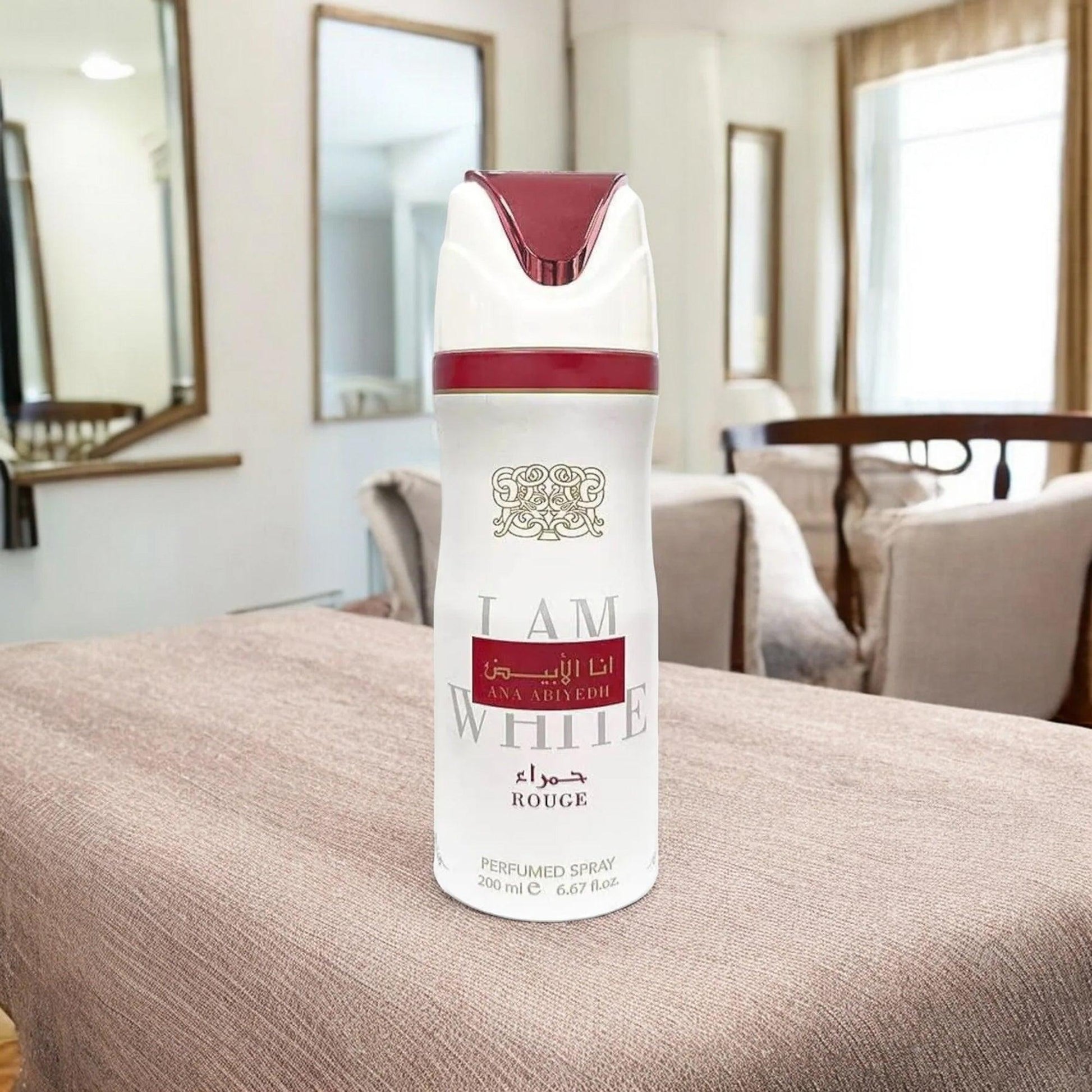 Lattafa Ana Abiyedh Rouge perfumed body spray 200ml in white and red bottle placed on a beige fabric surface with elegant living room background