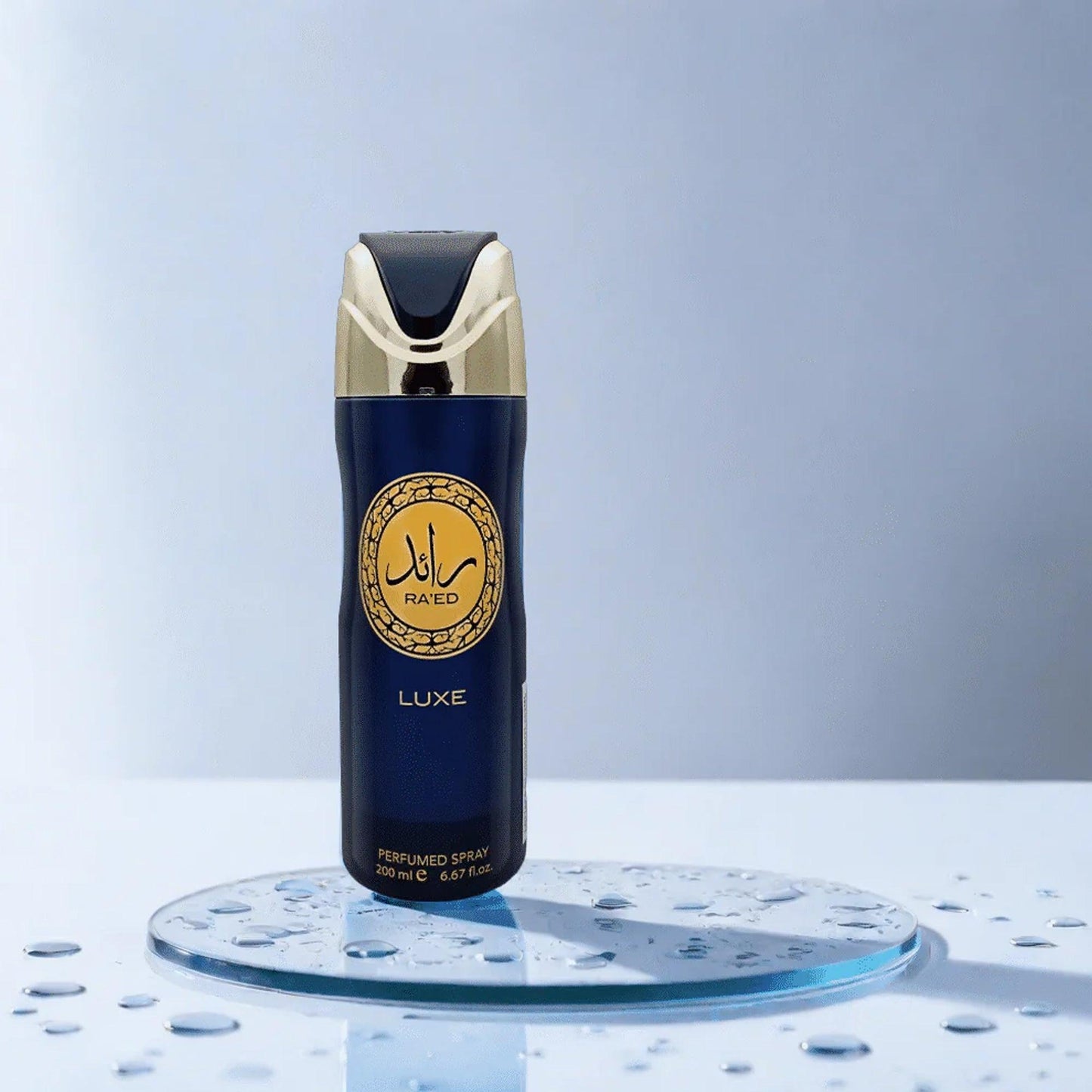 Lattafa Raed Luxe perfumed body spray 200ml in navy blue and gold bottle placed on a glass surface with water droplets and light blue background