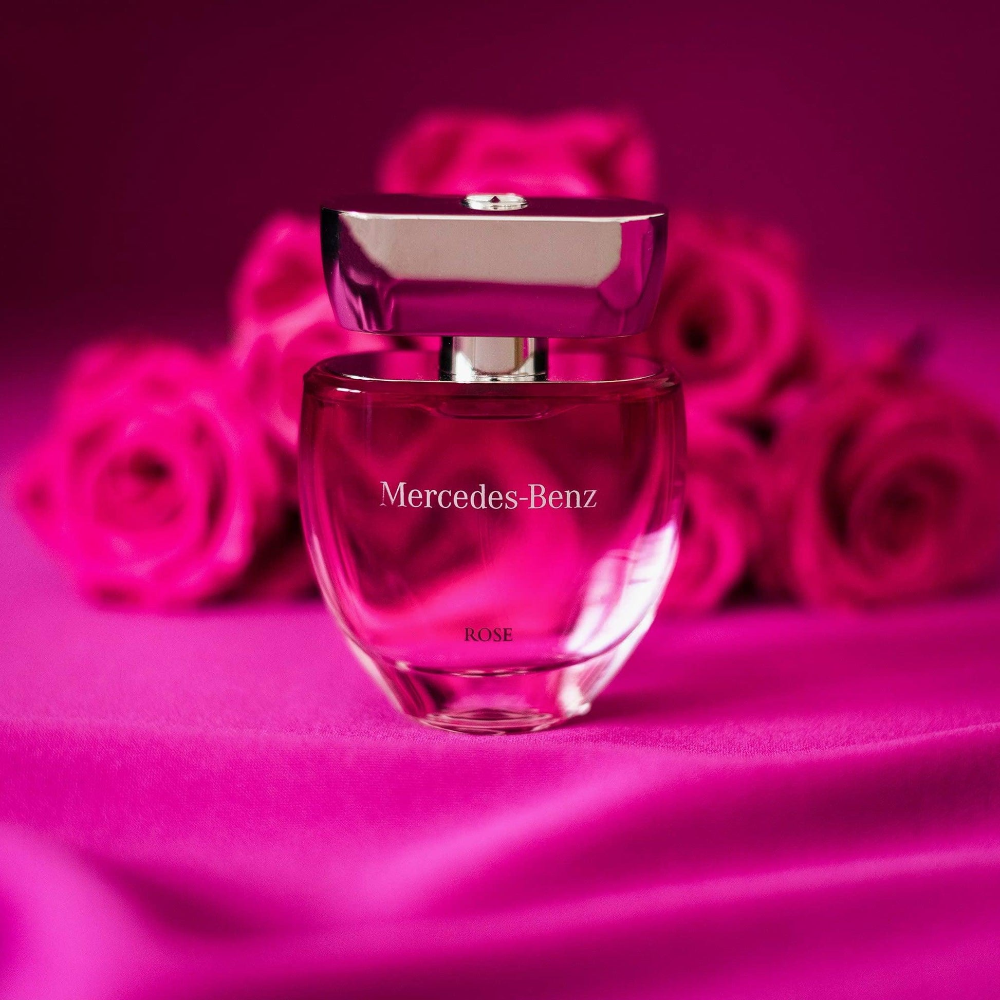 Mercedes-Benz Rose Eau De Parfum bottle on pink background with roses.