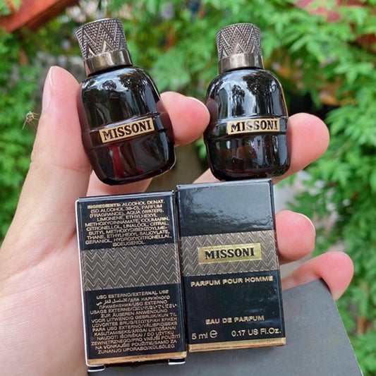 Missoni Parfum Pour Homme mini 5ml black perfume bottles with textured gold caps held by hand next to their matching black and gold packaging