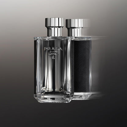 Prada Milano perfume bottle with sleek transparent glass and metallic silver cap reflected against a gradient grey background