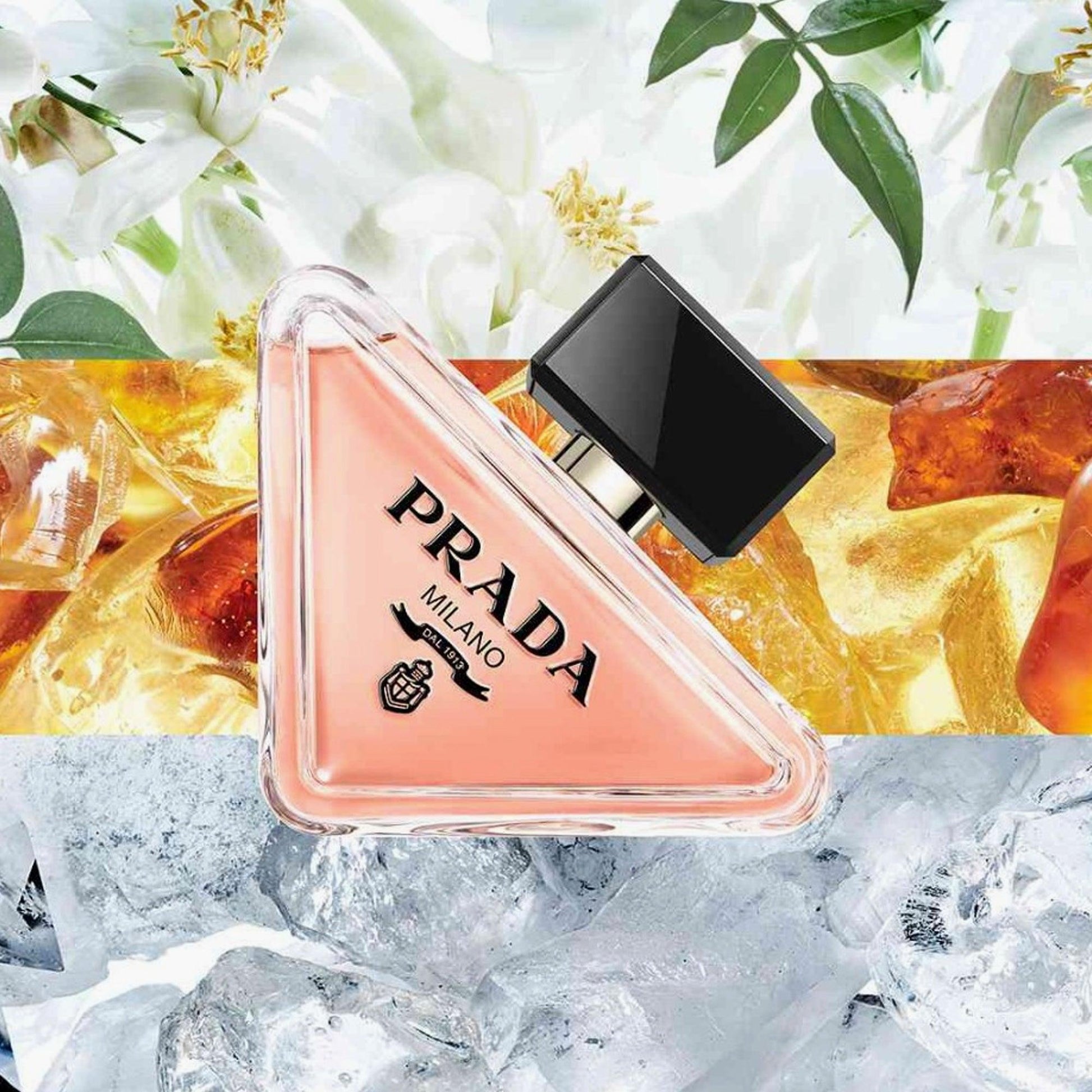 Prada Milano triangular perfume bottle with peach-colored liquid and black cap placed over floral, amber, and icy background textures
