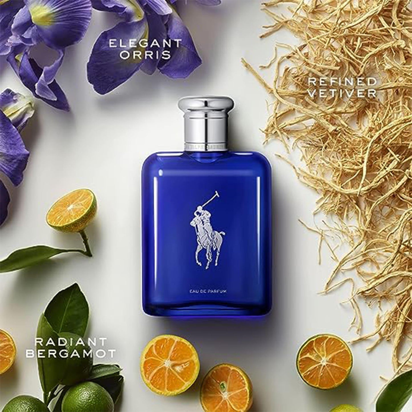 Ralph Lauren Polo Blue Eau De Parfum bottle surrounded by bergamot slices, vetiver roots, and purple orris flowers on a light background