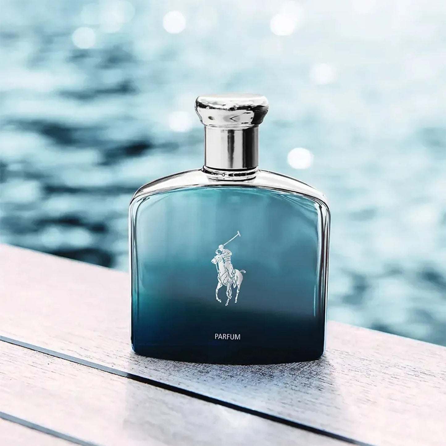 Ralph Lauren Polo Blue Parfum bottle placed on a wooden surface beside a shimmering water background, reflecting a fresh aquatic vibe