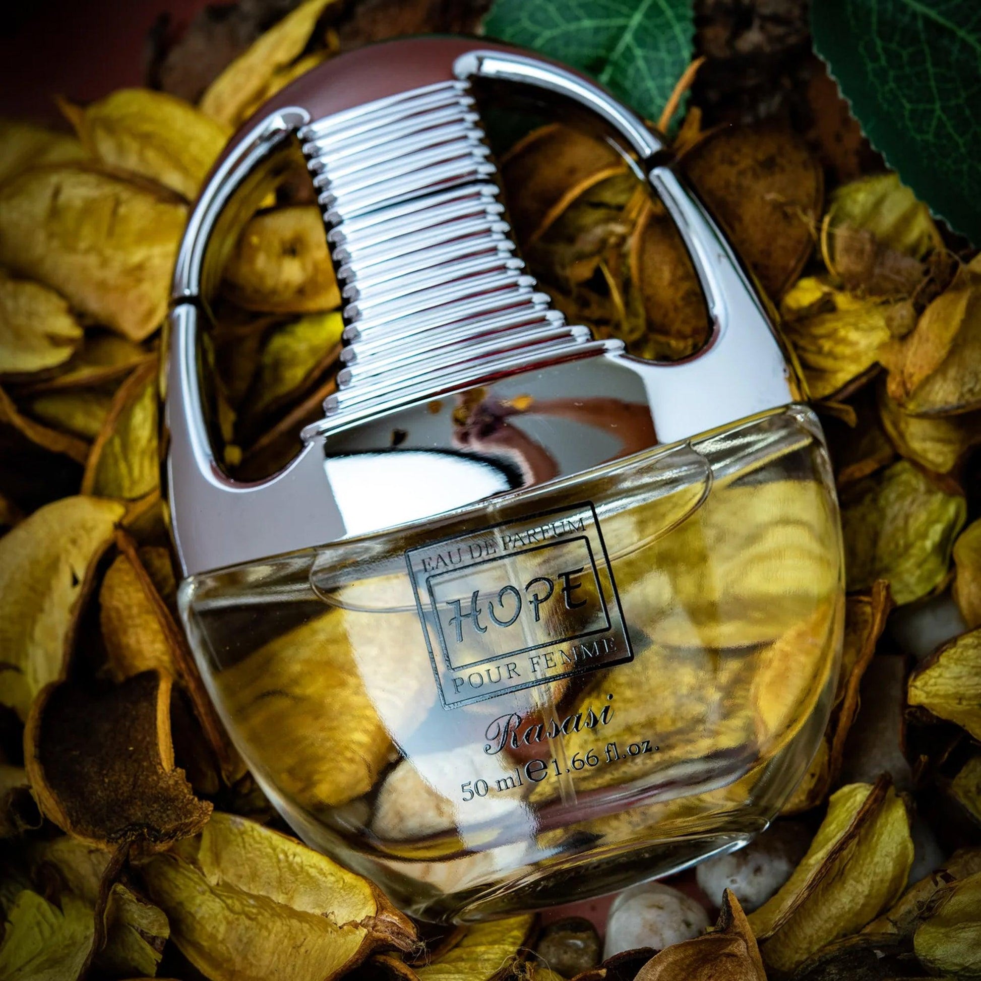 Rasasi Hope Pour Femme Eau De Parfum 50ml bottle with a metallic silver cap placed among dried golden petals and leaves, creating a warm, elegant background.