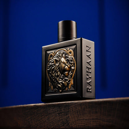 Rayhaan perfume bottle in matte black design featuring a golden lion emblem and embossed branding, placed on a wooden surface with a deep blue background