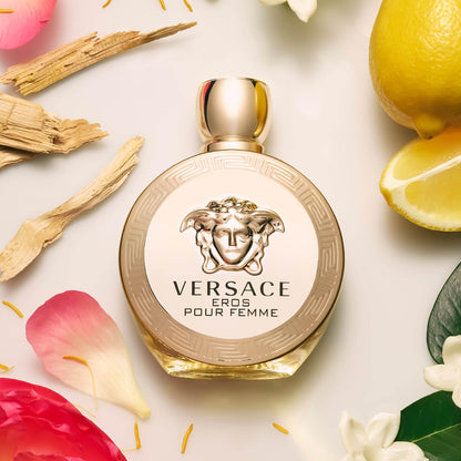 Versace Eros Pour Femme Perfume surrounded by petals and lemons on light surface