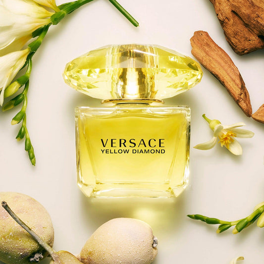 Versace Yellow Diamond perfume with flowers and wood on light background