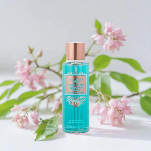 Victorias Secret Poolside Service fragrance mist 250ml bottle in aqua blue placed on a white surface with pink blossoms and green leaves in the background
