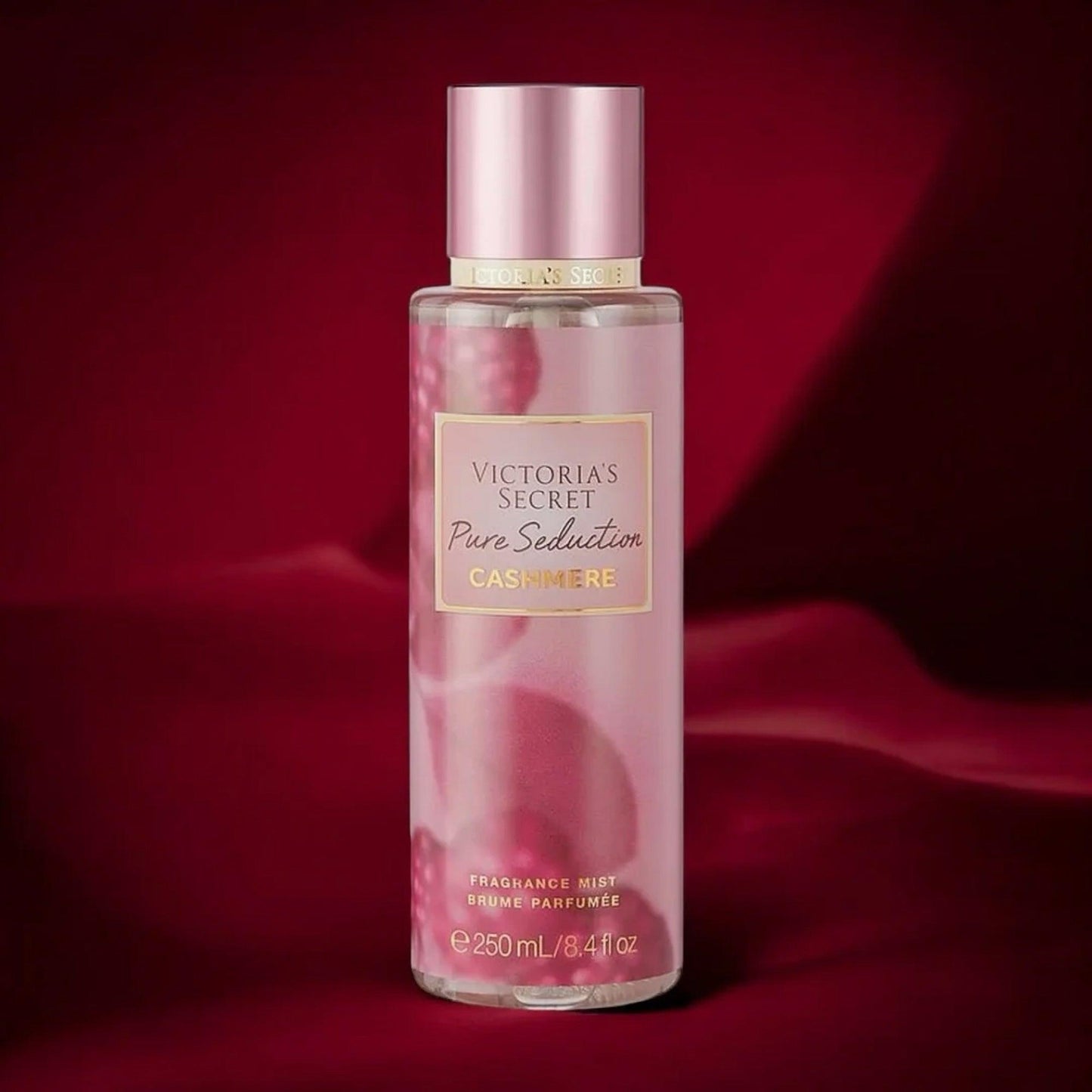 Victorias Secret Pure Seduction Cashmere fragrance mist 250ml bottle in soft pink design placed against a rich red satin fabric background