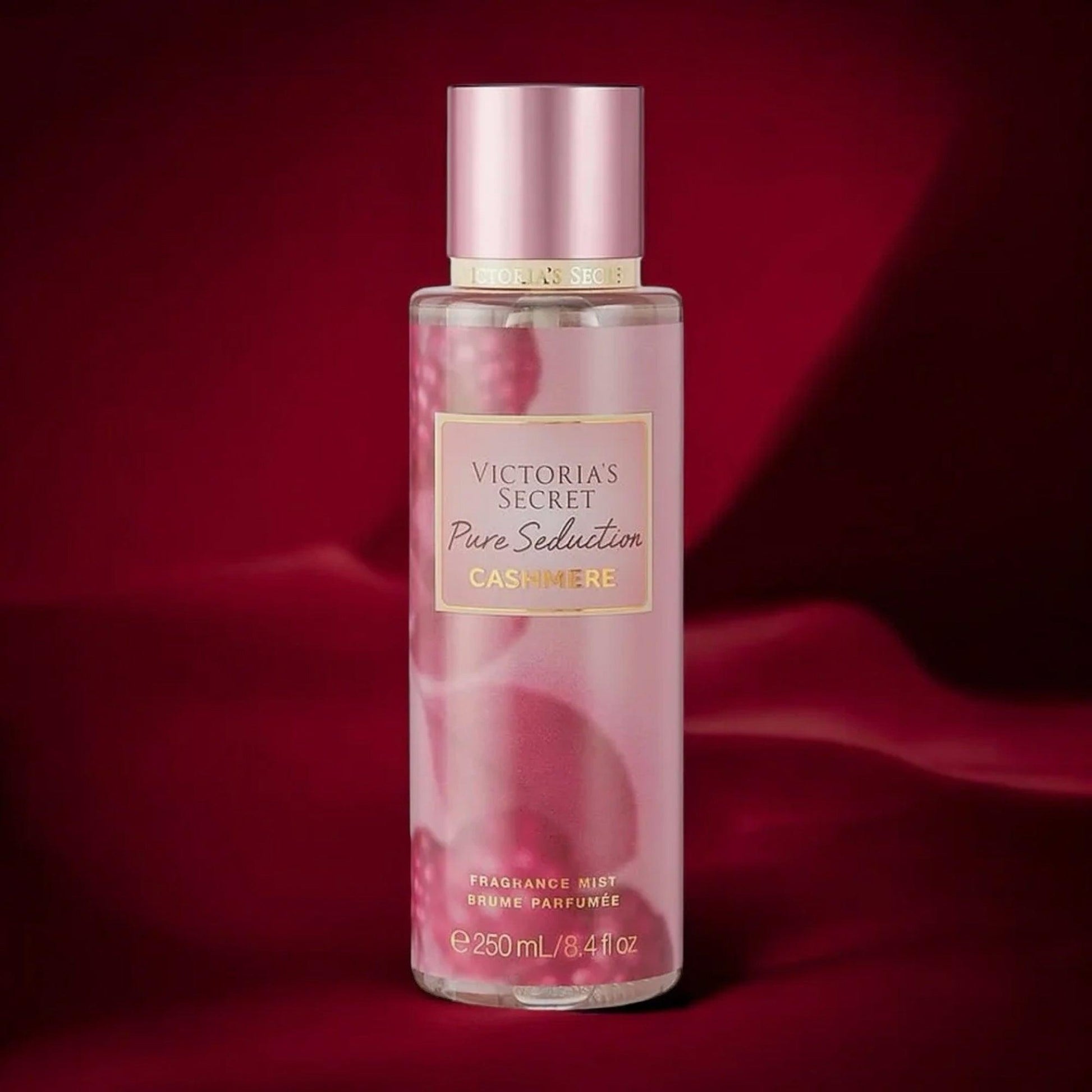 Victorias Secret Pure Seduction Cashmere fragrance mist 250ml bottle in soft pink design placed against a rich red satin fabric background