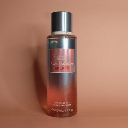 Victoria’s Secret Pure Seduction Splash fragrance mist bottle in red and metallic tones placed against a soft beige background